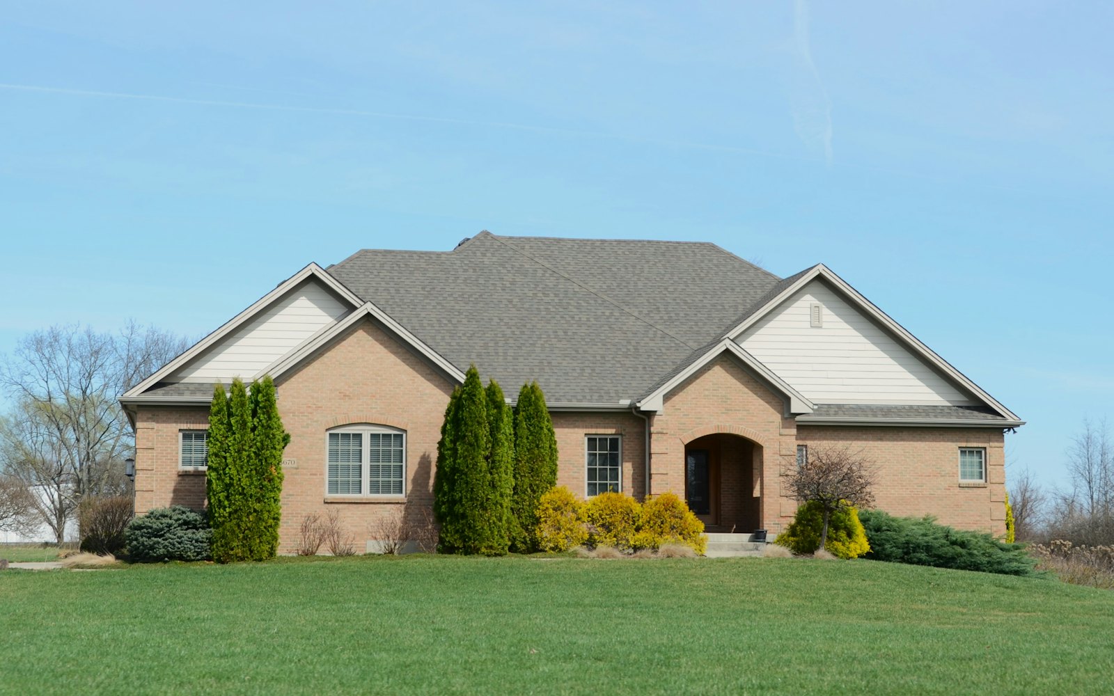 A brick house with a freshly mowed green lawn and trimmed shrubs
